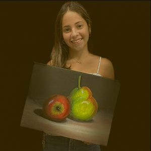 Picture of a student holding a painting of a pear and an apple.