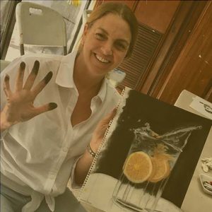 Picture of a student holding a painting of a gin and tonic.