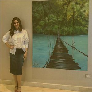 Picture of a student standing next to her big painting of a bridge over the sea.