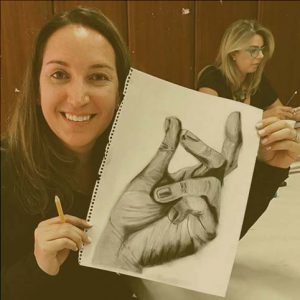 Picture of a student holding a drawing of a hand.